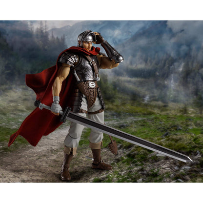 Berserk S.H.Figuarts  of Guts with armor, sword, helmet and a red cape standing in a mountainous landscape