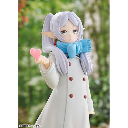 Frieren Blow Kiss Pop Up Parade figure   with white hair and blue scarf holding a pink heart, standing against a blurred natural background.