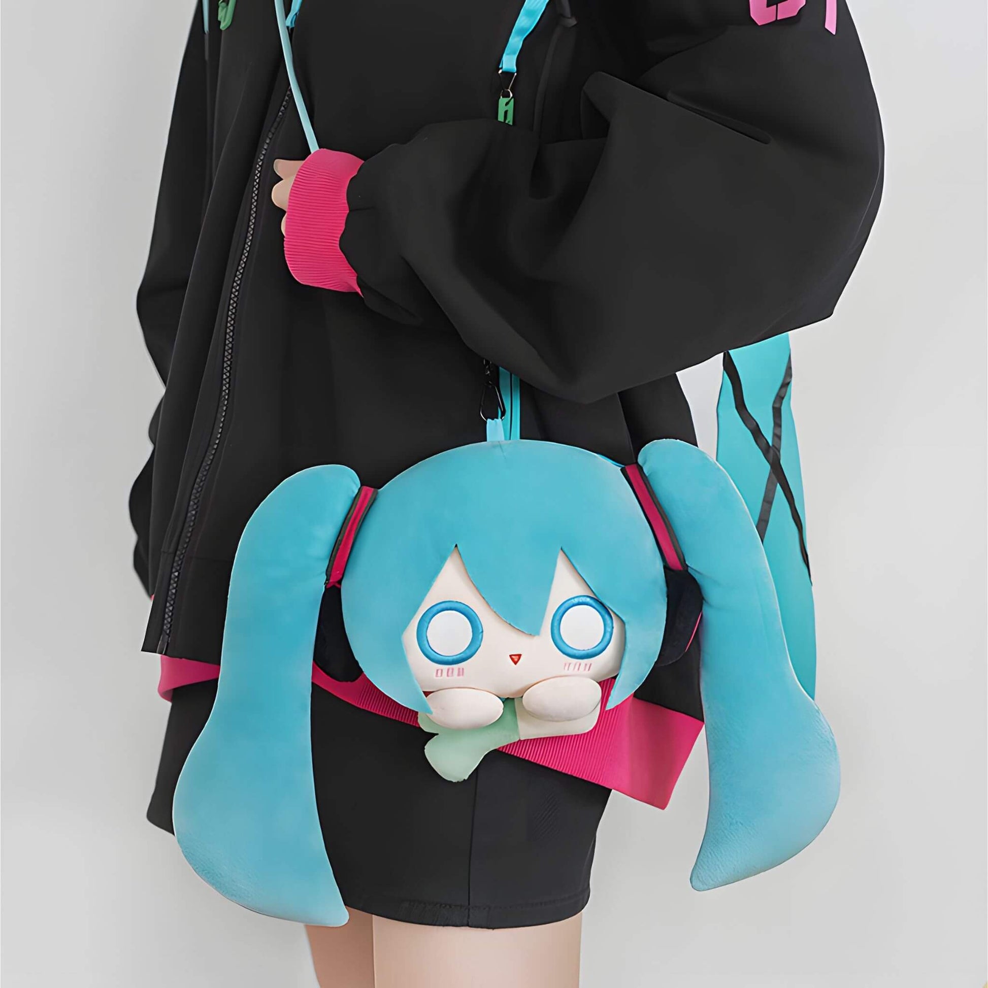Person wearing a black hoodie with a Hatsune Miku Plushie Pouch featuring blue hair and large eyes.