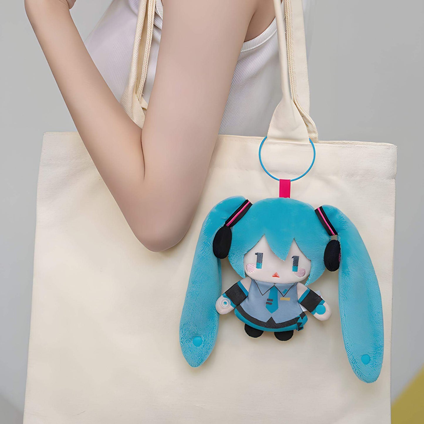 Hatsune Miku Keychain Pouch of a character with blue hair and headphones attached to a beige tote bag.