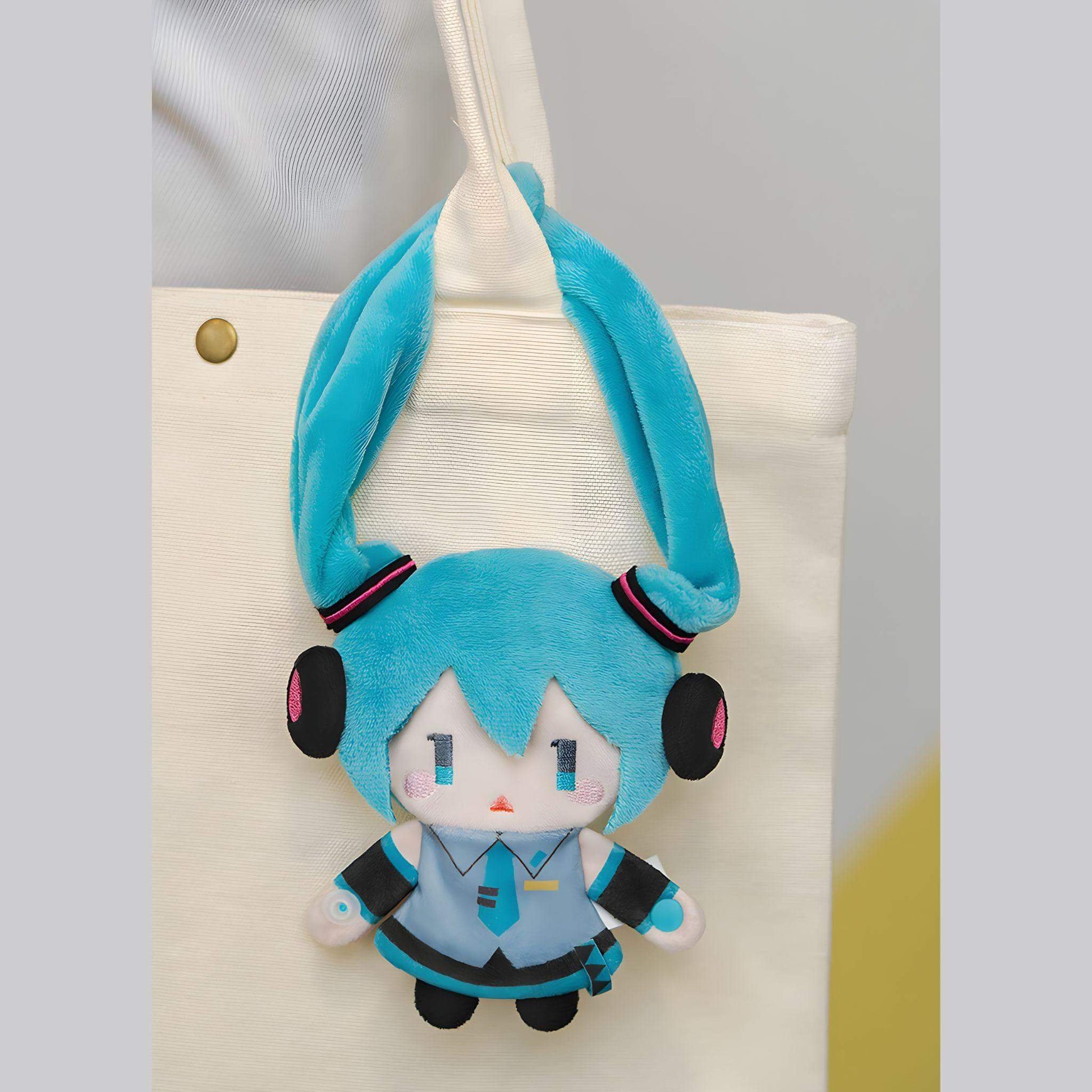 Hatsune Miku Keychain Pouch with blue hair and headphones hanging from a beige bag.