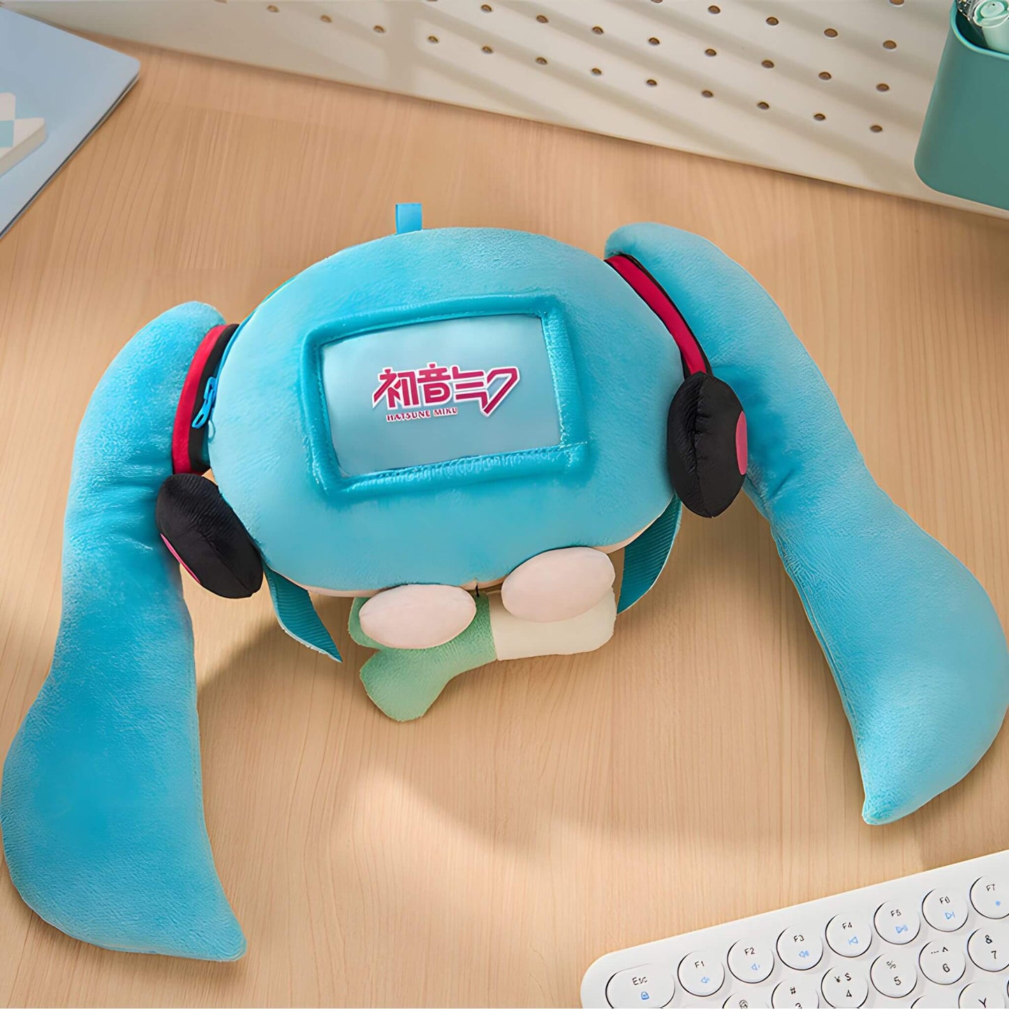 Hatsune Miku Plushie Pouch resembling a character with blue hair and headphones on a wooden surface.