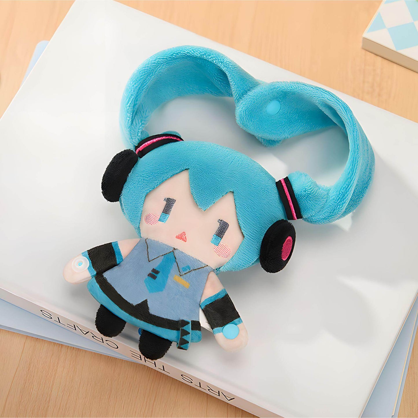 Hatsune Miku Keychain Pouch with blue hair and outfit on a book